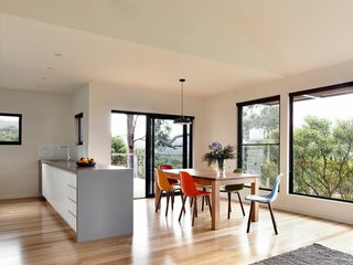 A Breezy Modern Beach House Sits Among the Trees in Australia - Photo 4 of 8 - The central living area features an open-plan kitchen, living space, and deck with views of Louttit Bay. To maximize energy savings, the house has a ducted reverse air cycle system from Fujitsu.