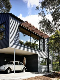 House of the Week: Party in the Hills - Photo 3 of 3 - Timber battens were used on north-facing windows to prevent excessive heat in the summer. The exterior is clad in Scyon’s Linea weatherboard and covered in Dylux’s Western Myall paint. Beneath the upper floor, a little nook makes for the perfect covered carport and storage spot for surfboards.