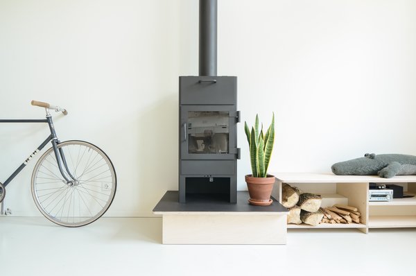 Modern home with living room and wood burning fireplace. The open-plan living room is Standard Studio architect and creative director Jurjen van Hulzen’s favorite part of the home. “Mom can cook, Dad can work or play piano, the kids can play. At nighttime there’s a fireplace and a nice sitting area,” says van Hulzen. “It really just has a super nice energy.” Photo 2 of The Schoolhouse