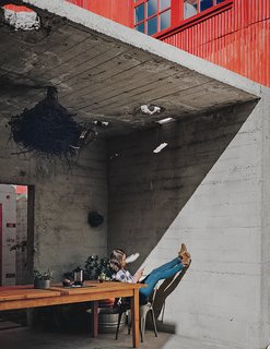 Abandoned Industrial Compound Becomes a Modern Home Base - Photo 1 of 11 - Kiyoko Loh relaxes inside a concrete structure, one of three original buildings that occupied the San Francisco property she and her husband, Elliot Loh, purchased in 2012. Working with architect Todd Davis, the couple decided to cut the bunker-like edifice in half and use it as an outdoor dining area that opens to a courtyard.