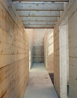 Abandoned Industrial Compound Becomes a Modern Home Base - Photo 9 of 11 - Once inside the property, a cedar-clad walkway runs parallel to the open concrete pavilion.