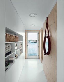The narrow entrance hall faces another door, which opens seaward. Built-in cabinets serve as both storage and display. The porthole mirror is by Jacques Adnet. 