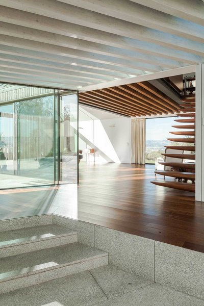 The connecting area between the four houses has an open joisted pine ceiling that offers a masterful transition between the coarse, weathered exterior and the polished rooms—all lined with smooth Sucupira wood and white plaster board. “We wanted to make a clear contrast between the interior surfaces of the house and the corresponding exterior surfaces,” de Carvalho says. Photo 4 of House of Four Houses modern home