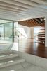 The connecting area between the four houses has an open joisted pine ceiling that offers a masterful transition between the coarse, weathered exterior and the polished rooms—all lined with smooth Sucupira wood and white plaster board. “We wanted to make a clear contrast between the interior surfaces of the house and the corresponding exterior surfaces,” de Carvalho says. Photo 4 of House of Four Houses modern home