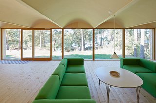 This Island Retreat Practically Embodies Simple, Rugged Scandinavian Design - Photo 4 of 4 - The site faces the sea but is surrounded by tall pines. The green sofas are from Hay.