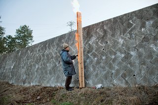 30 All-Black Exterior Modern Homes - Photo 12 of 30 - Fujimori demonstrates the process of charring cedar boards. After seven minutes, the length of time it takes to produce the proper amount of char, the boards are separated.
