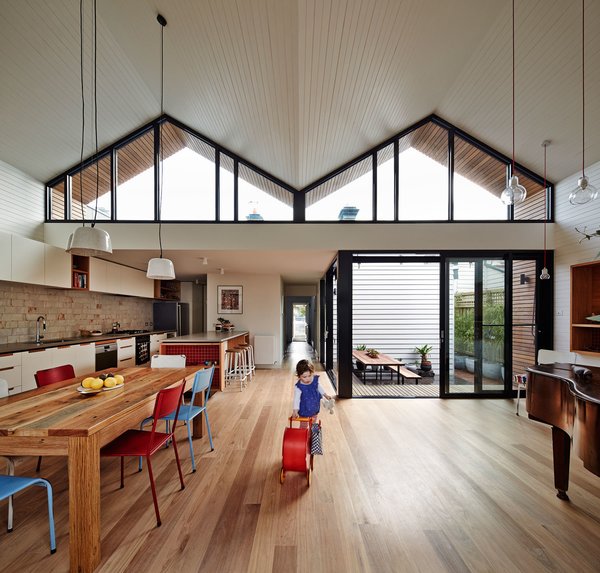 The roof’s geometric shape helps the interior feel more expansive than it is. Messmate timber floorboards and painted ceiling boards follow the lines of its double hip and draw the eyes upward. Powder-coated black aluminum window frames also accentuate its form. “We like the contrast of the white space with the gutsy black frames,” Bright says. Photo 3 of M House modern home