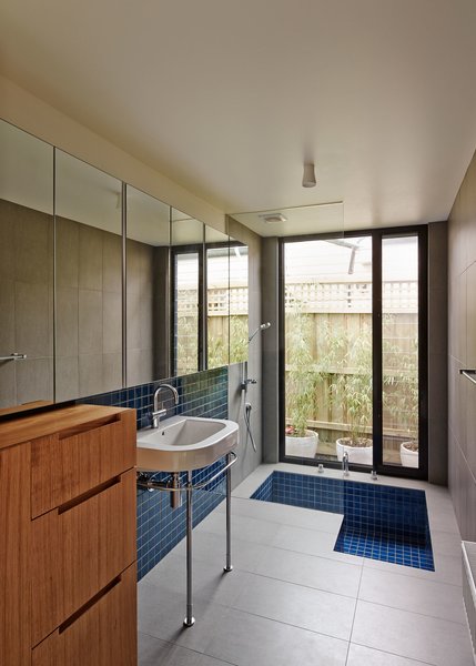 For the bathroom, the architects designed a clever tub that can serve as a shower, too. “Curved bath edges are not great to stand in so we wanted it to have a flat base,” Bright says. “We also didn't like that you would have to step over the edge of the bath to get in the shower. The solution to this was to sink it down.” The light is by Tub Design and fixtures by Duravit. Photo 8 of M House modern home