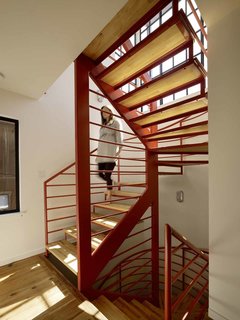 Fabricated by Stocklin Iron Works and designed by Nebolon, the orange staircase features steel railings and treads made from IKEA wood butcher blocks. "We designed the open staircase to make the trip to the second floor fun," the architect says.