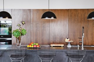 The First LEED Gold-Certified Family Home in San Diego - Photo 5 of 13 - In the kitchen, custom walnut cabinetry and Caesarstone counters are paired with Bertoia stools and Ikea pendant lamps.