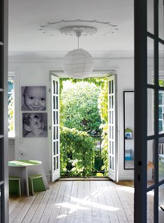 A Cramped Attic Became a Sunny Dining Room in this Renovation of a Copenhagen Tudor - Photo 8 of 12 - Original 1925 details include stucco molding throughout the house. A Small-Design Circle table and stools echo outdoor greenery in the room shared by Elliott and Mateo, ages 12 and nine.