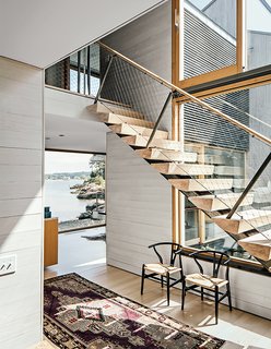The white cedar board paneling in the interiors mimics the exterior; the ones inside are bleached for a lighter finish. Fixed glass picture windows are by Town & Country Glass. Unalam and JIG Design Build fabricated the staircase with ash risers on a single stringer, a Gray Organschi hallmark.