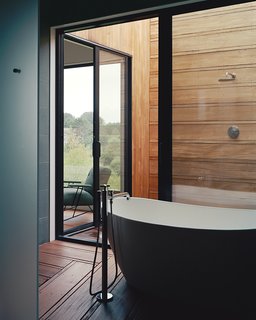 The master suite’s bathroom unfolds from a glass-walled bathing room, outfitted with a Signature Hardware tub and Lefroy Brooks fixtures, to an open-air shower.