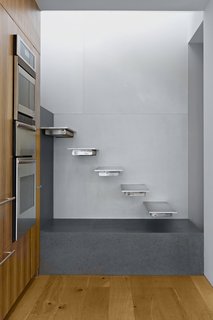 10 Dazzling Modern Staircases - Photo 3 of 10 - Slade Architecture renovated a penthouse in New York City to include this open-tread, railing-free staircase. Each cantilevered tread is supported by stainless-steel tubes. The use of aluminum on the treads keeps them feeling light and airy as they reflect light from the windowed kitchen.
