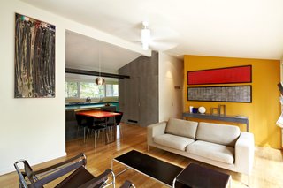 Modern Kitchen Renovation with Mid-Century Roots - Photo 6 of 6 - Today, Bloomberg's living room flows naturally into the kitchen. The living room's floor-to-ceiling glass windows offer loads of natural light to a previously tucked-away kitchen. The yellow wall and a few classic pieces of furniture from the modernist canon complete the renovation. Photo by: Greg Powers