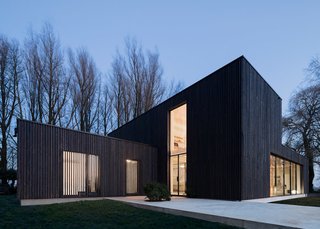 This Blackened Timber House Triumphantly Emerges After a Fire - Photo 2 of 6 - "We wanted the wood to appear as natural as possible, so leaving the larch untreated was the first choice," Bas explained. But the shape of the house would make the wood turn gray unevenly, so they blackened the larch. "The clients were excited with the dark color as it helps the house blend into the trees. They didn’t want the anything excessive or showy." But blackened timber comes with its own challenges. Since it absorbs more heat, a larger air cavity was built behind the wood to keep it cool.