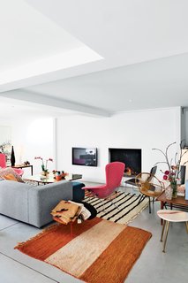 The stars of the living room are a pair of pink Bird chairs by Harry Bertoia for Knoll. Both the marble-topped occasional table and the wood table are vintage, the antique rugs are from Morocco, a Low Pad chair by Jasper Morrison for Cappellini sits near the fireplace, and the brass-and-steel coffee table was designed by Poorter and Holdrinet.