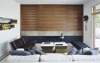 The living room TV cabinet is by Muti Kitchen & Bath. It's surrounded by a sofa and chairs from ELTE and side tables from Kantelberg + Co. Matte-finish Chantilly Lace paint from Benjamin Moore provides a bright backdrop.