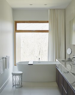 The master bathroom features Pro Tec windows framed in European pine, a freestanding tub by Wetstyle, and a marble vanity top from Ciot.