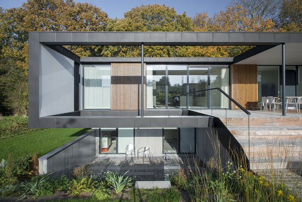 Located in Aarhus, Denmark, Villa R is a minimalist, serene structure clad in zinc panels. "The objective was to create a house that brings the forest inside through large glass panels—and create an ever-changing seasonal backdrop for the interior living spaces," stated the architecture firm, C.F. Møller, of the 3,200-square-foot abode. Photo of Villa R modern home