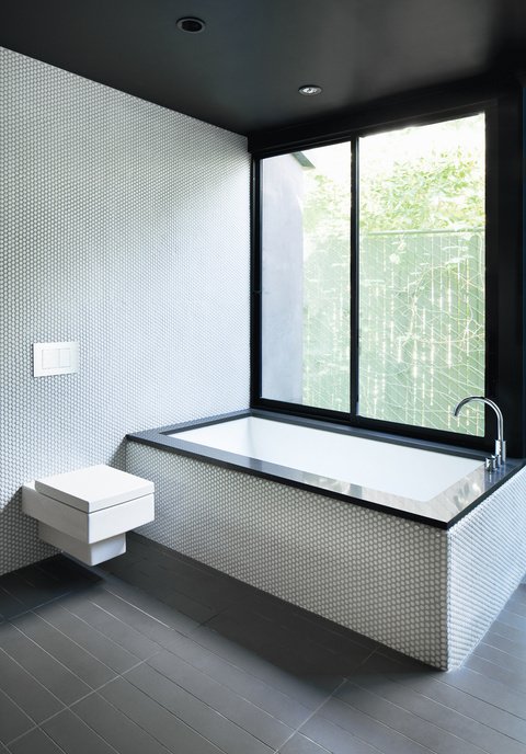 40 Modern Bathtubs That Soak In the View For the bathroom inside a renovated Hollywood bungalow, architect Noah Walker used a simple palette of gray and white tile, black countertops, and stainless steel fixtures.