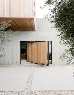 A Texas Couple Builds Their Cast-In-Place Concrete Dream Home - Photo 1 of 17 - A pivoting door, also made of larch, provides a shortcut to enter the structure as an alternative to the main courtyard entrance.