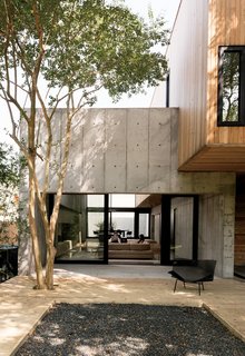 A Texas Couple Builds Their Cast-In-Place Concrete Dream Home - Photo 5 of 17 - Sliding doors from Western Window Systems connect the living room and the deck, which is made of pressure-treated pine planks surrounding a black gravel pit.