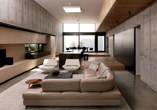 A Texas Couple Builds Their Cast-In-Place Concrete Dream Home - Photo 6 of 17 - The living room features a sofa from Roche Bobois, Metropolitan armchairs by Jeffrey Bernett for B&B Italia, and a Good Morning table in copper and Anytime table in anthracite frosted glass from Ligne Roset. The rug is by Tissage.