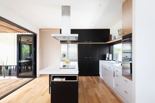 A Modular Beach Home in Australia Allows One Family to Keep an Eye on the Surf - Photo 7 of 8 - In the kitchen, an island countertop serves as a mixed-use area for cooking, storage, and seating for up to five people. The room opens up to an outdoor dining area.