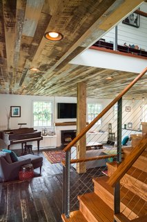 The staircase works as a visual transition from the cozy first level to the more modern second floor. When standing downstairs, the staircase pulls away from the dark anchoring floorboards with angled steel beams, stainless steel cables, and wood caps. "It’s thin and light so that it wouldn’t impede connection to the first floor," says Michael. "It’s meant to be pretty modern, but the wood cap softens the look a little, and makes the experience of touching the railing softer."