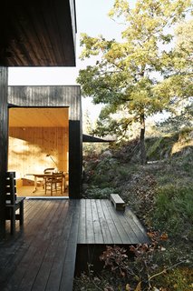 30 All-Black Exterior Modern Homes - Photo 30 of 30 - The house is divided into three sections connected by a series of outdoor galleries. "When I walk from one room to another, I have to go outdoors and feel the weather and nature—rain, cold, and sun," says Sævik. <br><br>Instead of emphasizing the expansive panorama of oak, pine, and aspen trees, the house frames select views—a move inspired by Japanese design.