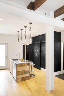 An Old Row House in Montreal Gets a Colorful Modern Upgrade - Photo 5 of 10 - The couple's kitchen is an exercise in both sustainability and creativity. The island is wrapped with reclaimed scrap wood uncovered from the house during demolition. Chalkboard walls provide a whimsical canvas for graphic images and notes.