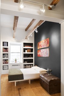 An Old Row House in Montreal Gets a Colorful Modern Upgrade - Photo 9 of 10 - Boasting 11-foot ceilings, the master bedroom showcases and celebrates numerous antiques unearthed from the home during demolition. Midcentury enamel Coke signs, found under layers of rotting wood, became graphic accent pieces. A stately trunk, also uncovered from the renovation, is a centerpiece of the room and home, which is coincidentally located on Grand Trunk Street in the Pointe-Saint-Charles neighborhood of Montreal.