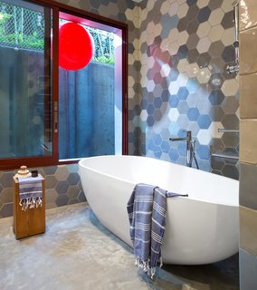 The master bathroom’s Aquabrass tub is next to a window lined by fumed oak millwork framing a tethered red balloon, displayed for levity.
