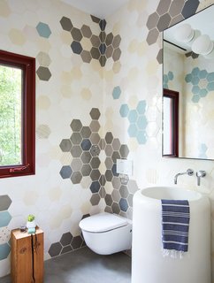 A sculptural freestanding washbasin by Gessi is found in the first-floor powder room. The hex tiles are courtesy of Dear Human.