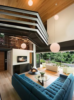 An Angular Futuristic House in Georgia - Photo 3 of 7 - In the living room, Svenson opted for wide-plank ash floors and a fireplace from Malm. The room connects to the screened-in porch (accessed by folding doors) and has a view of the split-levels above. The jagged bridge leads to the residents' writing studios. "I wanted something that feels a little scary, that gives you energy when you walk across it," says Svenson.
