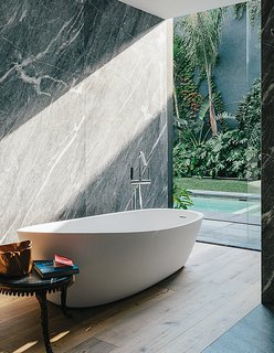 A Lush Retreat With a Sheltered Rooftop Pool in Mexico City - Photo 8 of 14 - An Almond bathtub by Porcelanosa is accented by a tub filler from Hansgrohe.