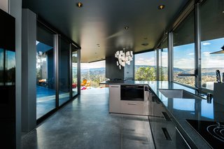 Darker Caeserstone countertops and concrete floors complement the angularity of the kitchen plan. An Ingo Maurer Zettel’z 5 chandelier hangs over the dining room table.