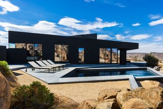The pool is framed by angular concrete paths reflecting the natural geometry of the site.