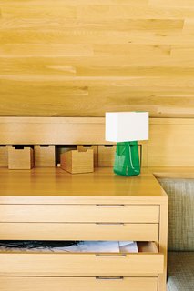 The main built-ins—a sofa bed, table and chairs, and plenty of storage—run the length of the space and are tucked snugly beneath the ceiling. The green Tube Top 14 lamp by Pablo Pardo is from Relish Design.