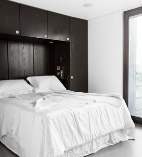 The master bedroom echoes the house’s black-and-white exterior and includes a custom-built storage unit that the architect designed for the space.
