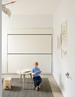 How One Family of Three Does It All in 675 Square Feet - Photo 4 of 14 - In his room, Finn sits on a Stump stool by Kalon Studios at an oak table from Canvas Home. The flat jute rug is from ABC Carpet & Home; the stainless-steel door hardware is by Emtek.