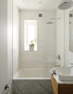 How One Family of Three Does It All in 675 Square Feet - Photo 13 of 14 - All of the apartment’s fixtures are by Kohler, including the kitchen sink and faucet as well as the Tea-for-Two bathtub, Vox square sink, and Catalan mirror in the bathroom. The Thassos marble subway tile is by Ann Sacks.