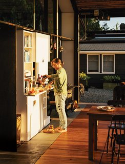 Renovated Garage is the Ultimate Modern Party Space - Photo 7 of 9 - Ruth preps drinks at the Corian bar. Miscellaneous found chairs surround a Roy McMakin dining table.