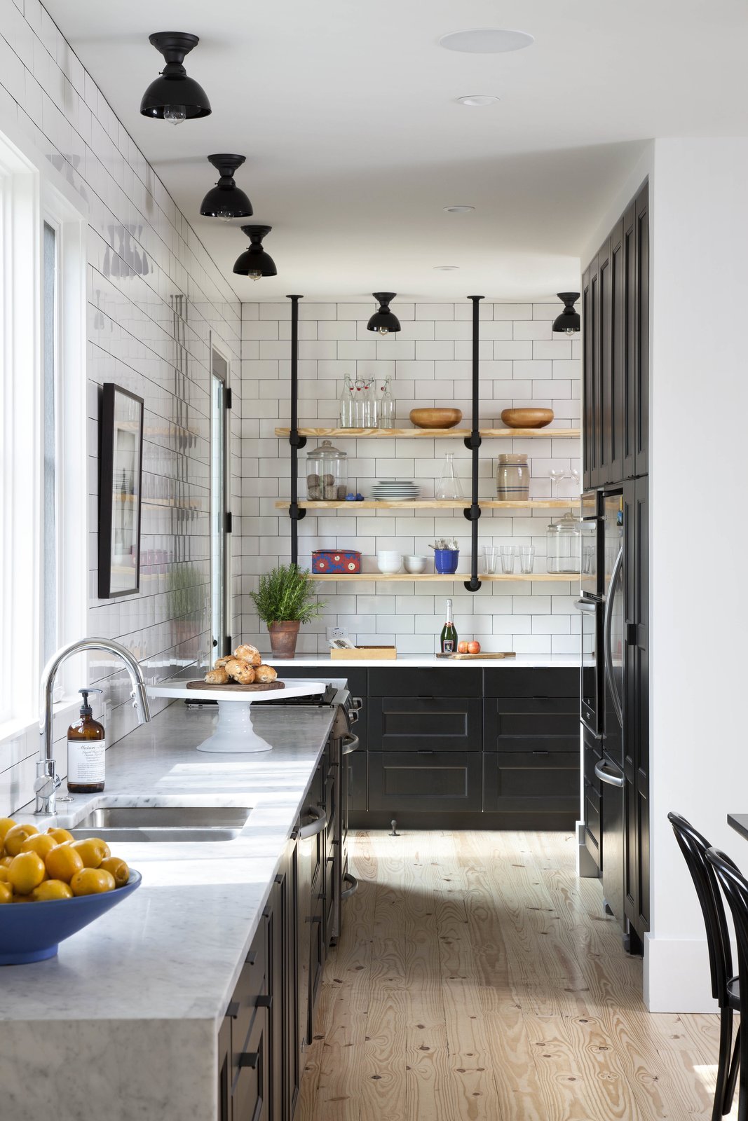 Flournoy’s partner is a baker, and was given free reign to develop a kitchen that met his needs. The space combines black, Shaker-style cabinets, white subway tiles, Carrera marble countertops, and wooden floors to create a balance between rustic warmth and industrial simplicity.