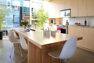The Architect Next Door - Photo 8 of 9 - The kitchen features stainless steel prep counters, a Samsung stove, and Panasonic over-the-range microwave. The room is bordered by two full walls of windows, allowing light to flood the space at all times of the day. A custom birch butcher block table furnishes the family gathering space.