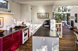 This house in Carmel by the Sea is enlivened by its very red kitchen cabinetry. By knocking down a dividing wall, the architects opened the kitchen up to the rest of the living space. Ikea red lacquer cabinetry and Caesarstone countertops replace dingy cupboards and old-fashioned finishes. Stainless steel appliances help ground the airy, open space.