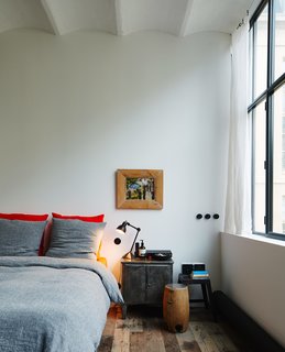 In the bedroom, a 1930s painting by French artist Louis Parrens hangs above a vintage nightstand with a Lampe Gras light, designed in 1921 by Bernard-Albin Gras. The bed is dressed with Merci linens.