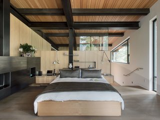 A Forest Sanctuary Designed to Support Autistic Triplets, Their Parents, and a Host of Caregivers - Photo 7 of 19 - Hawkins created the built-in anigre bed and side tables in the master bedroom. Chenault designed the bedding; the sconces are from Artemide.