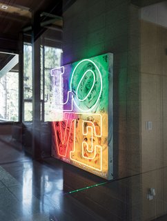 A Forest Sanctuary Designed to Support Autistic Triplets, Their Parents, and a Host of Caregivers - Photo 15 of 19 - On a concrete wall near the stairway off the main hallway hangs an artwork that depicts the children. Nick conceptualized the piece with painter Bryce Chisholm and artist Jeff Johnson, who did the custom neon work. The floor is also made from concrete.